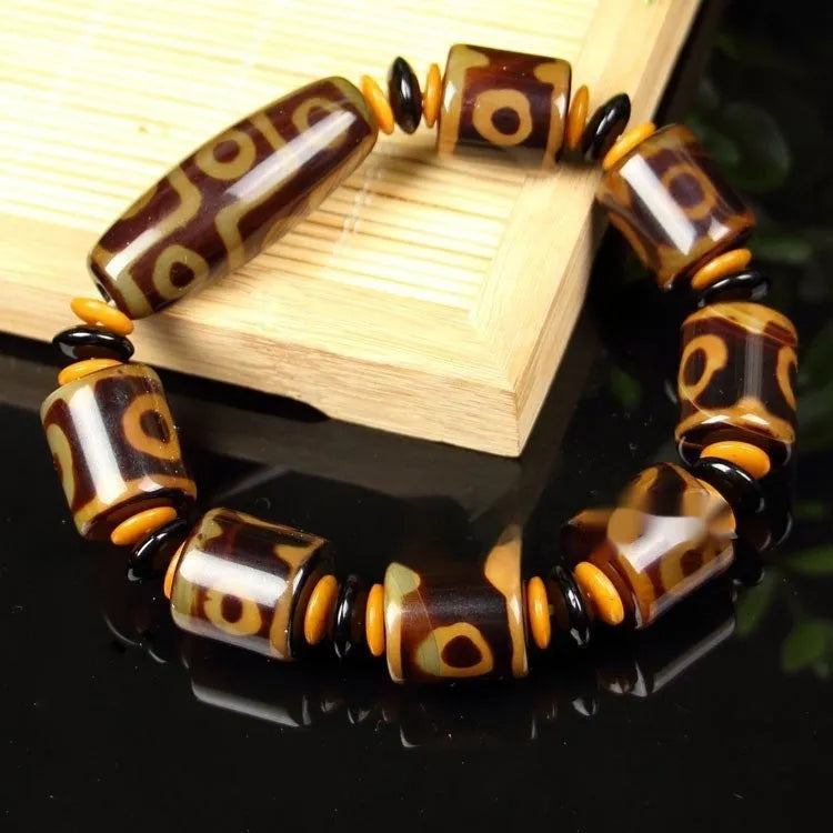 Distressed agate Tibetan bead bracelet with three-eye motifs and polished finish.