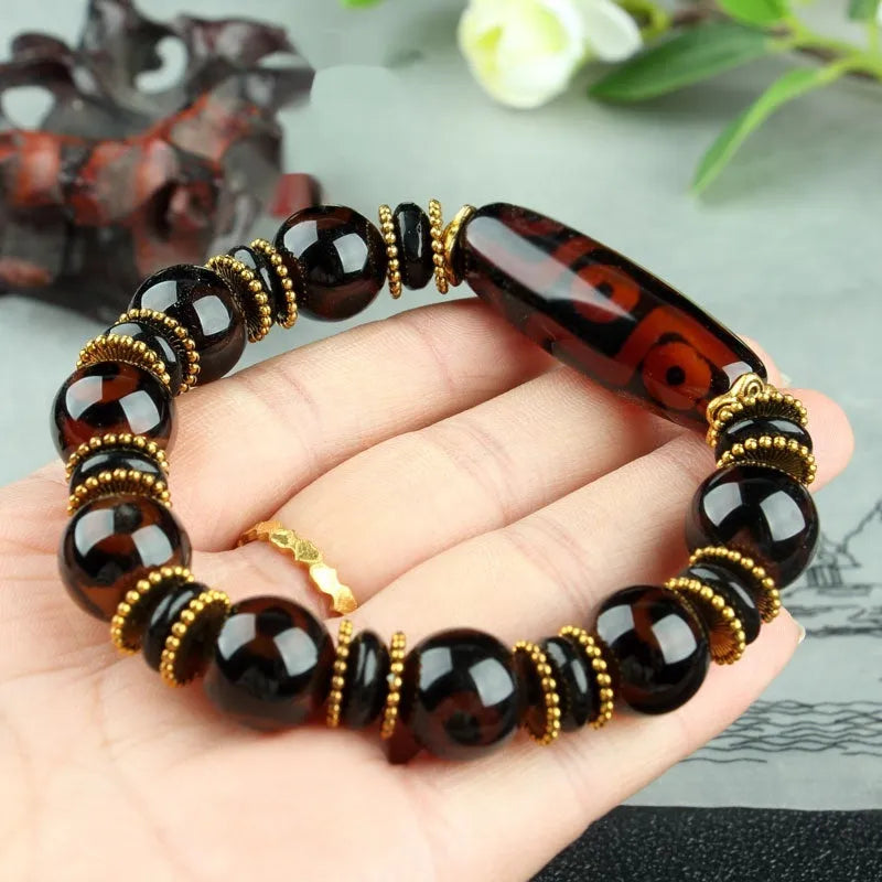 Distressed agate Tibetan bead bracelet with three-eye motifs and polished finish.
