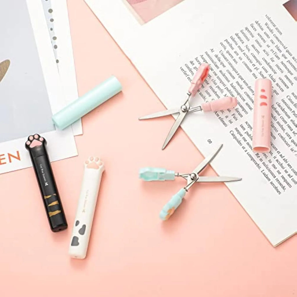Closed folding mini scissors with cat paw design on handles in blue, pink, black, and white colour options.