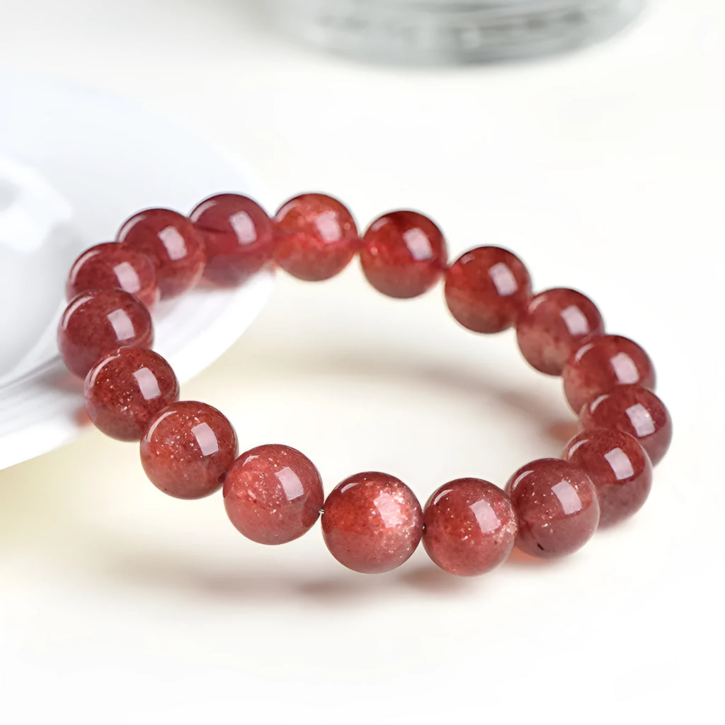 Natural cherry red strawberry quartz bracelet with polished geometric beads on a white background.