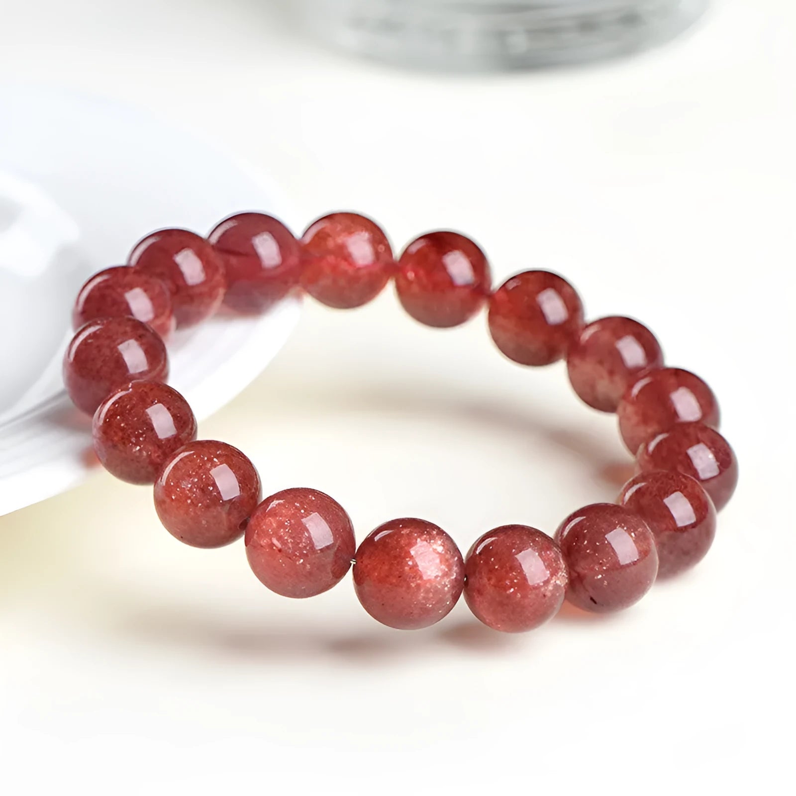 Natural cherry red strawberry quartz bracelet with polished geometric beads on a white background.
