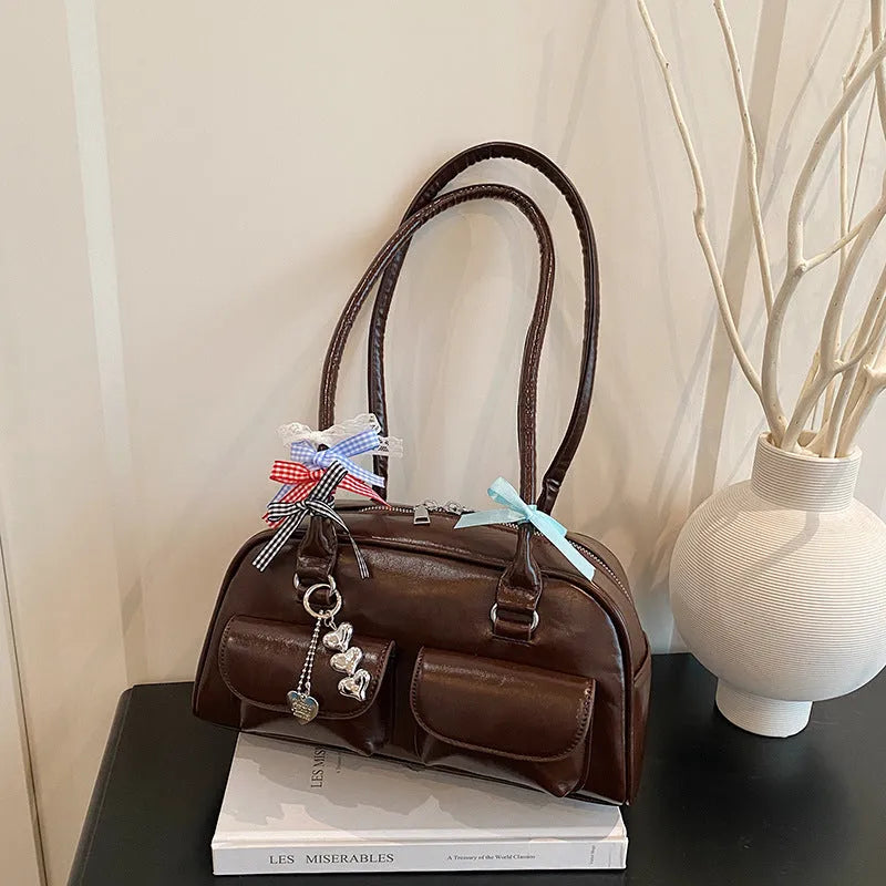 Black retro women's pillow-shaped handbag with double shoulder strap and flap closure.