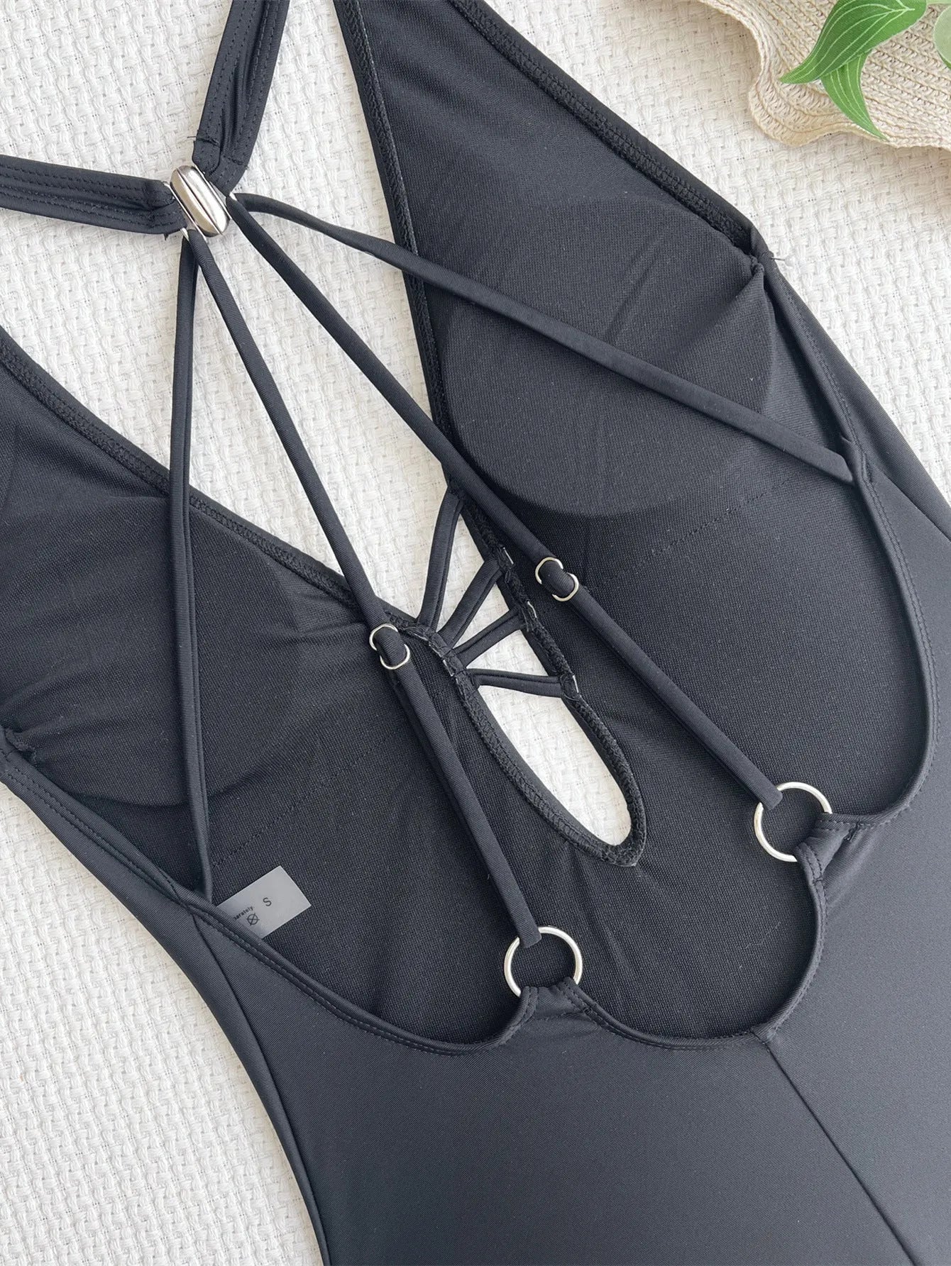 Women's solid black one-piece nylon swimsuit laid flat, showing its classic design and straps.