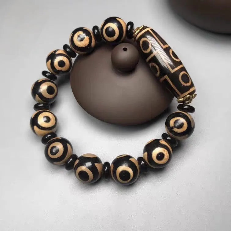 Distressed agate Tibetan bead bracelet with three-eye motifs and polished finish.