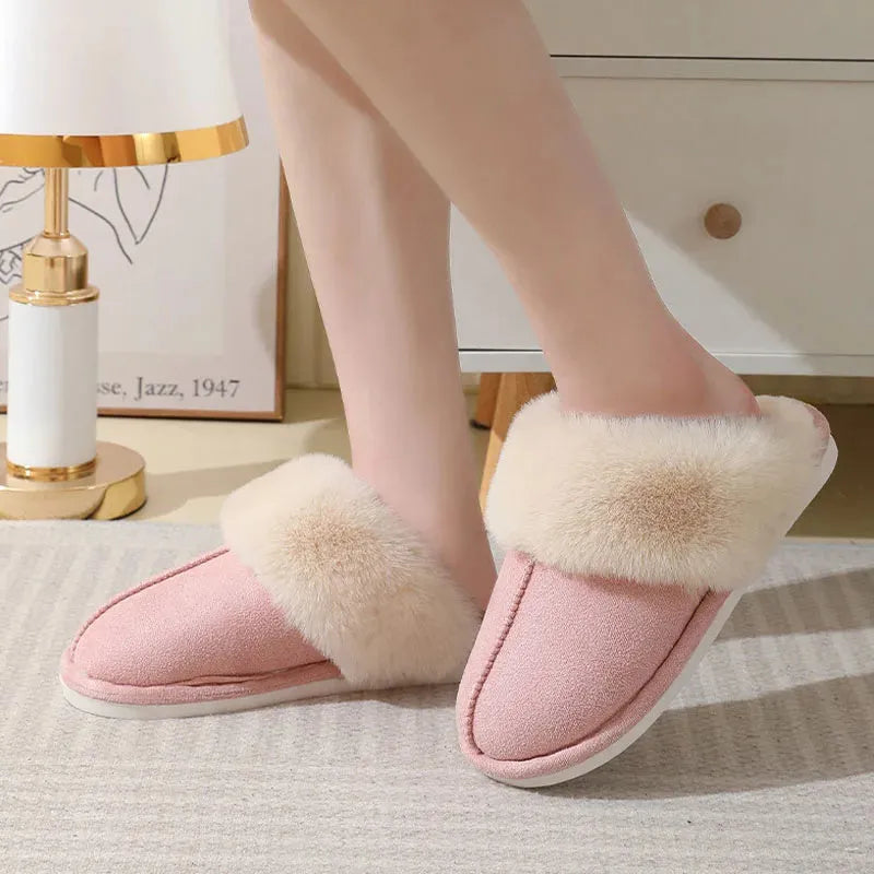 A pair of plush indoor slippers with a round toe, flat heel, and stitching detail, shown in one of five available colours.