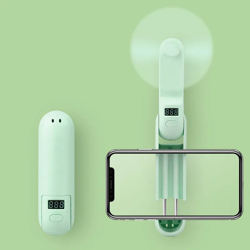 Green folding mini fan with plastic blades collapsed for compact storage