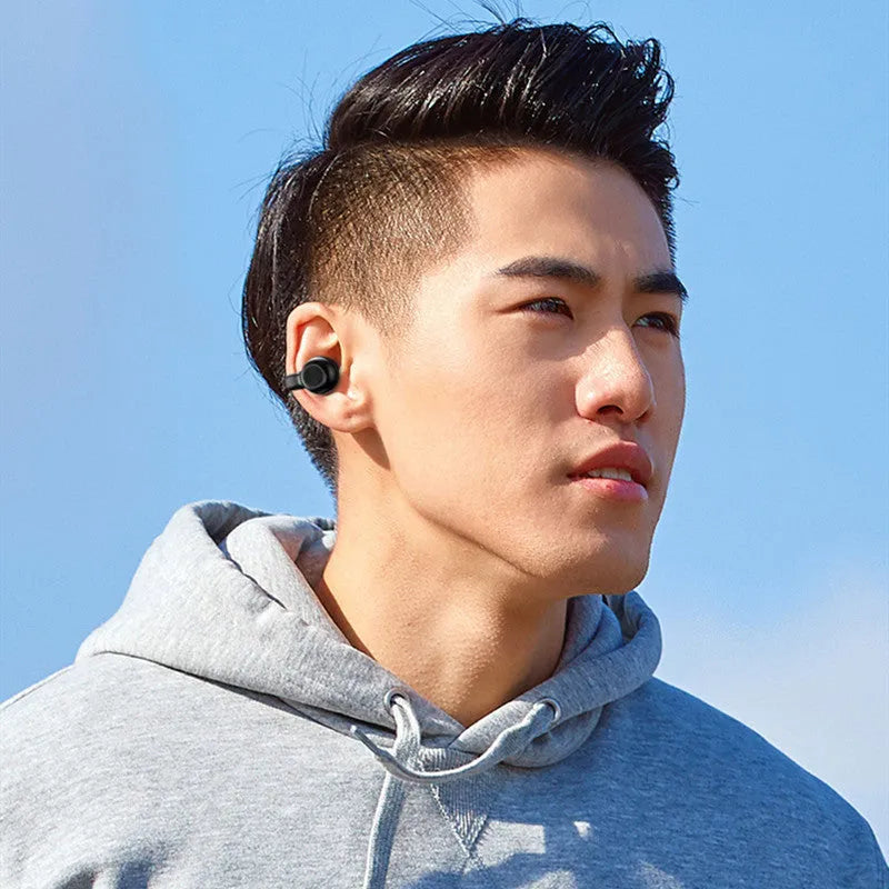 Black clip-on wireless bone conduction Bluetooth headset for sports, shown with charging cable.
