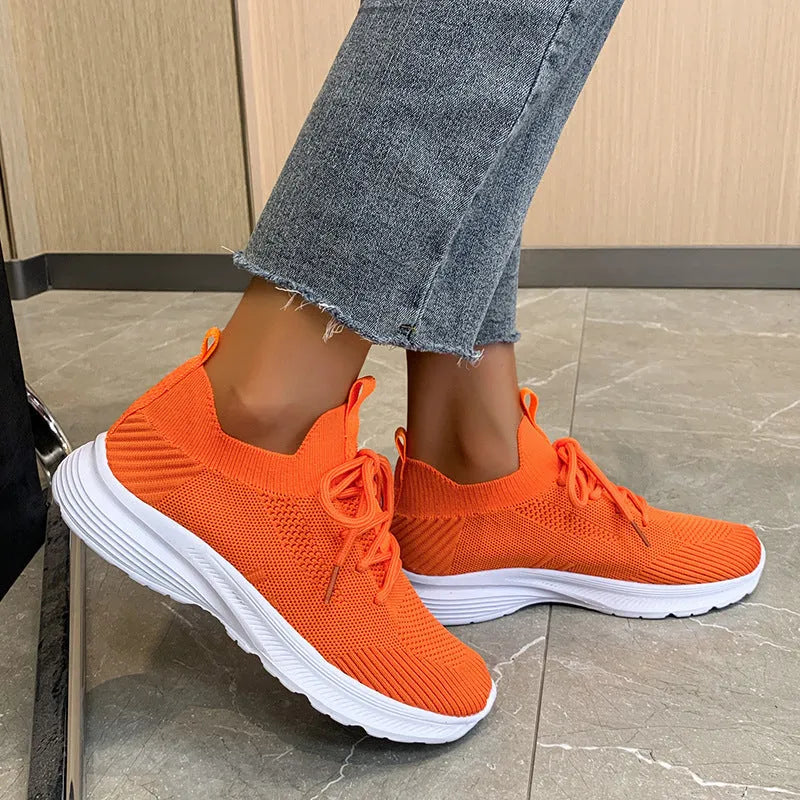 Women's creamy white low-top running shoes with a Flyknit upper and mesh detailing on a flat rubber sole.