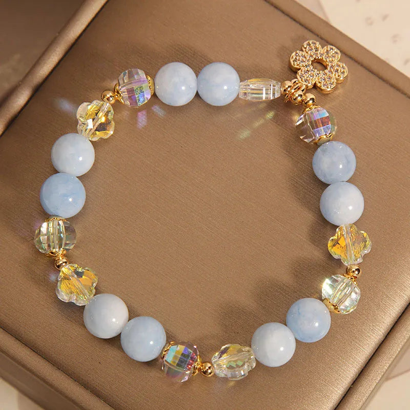 Women's aquamarine crystal bracelet with four-leaf clover charm and pearl accents on wrist
