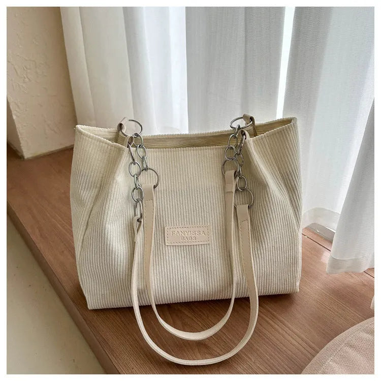 Corduroy one-shoulder tote handbag in a horizontal square shape with a three-dimensional outer pocket.