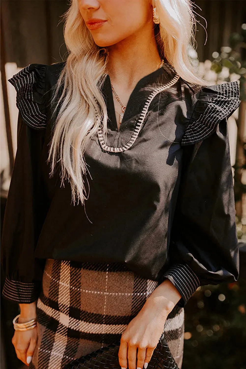 Black V-neck long sleeve blouse with ruffle detail and contrast stitching.