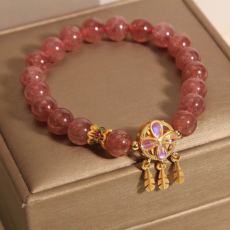 Women's strawberry quartz bracelet with four-leaf dream catcher ball pendant on wrist
