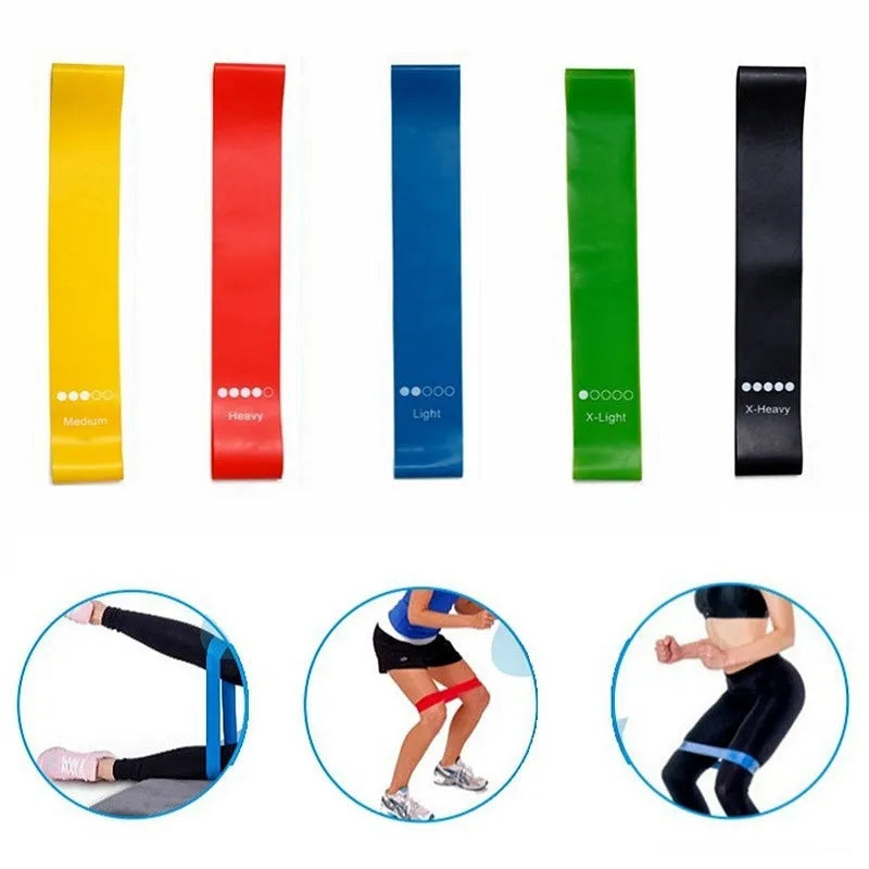 Five colour-coded yoga tension straps for resistance training laid flat showing green, blue, yellow, red, and black options