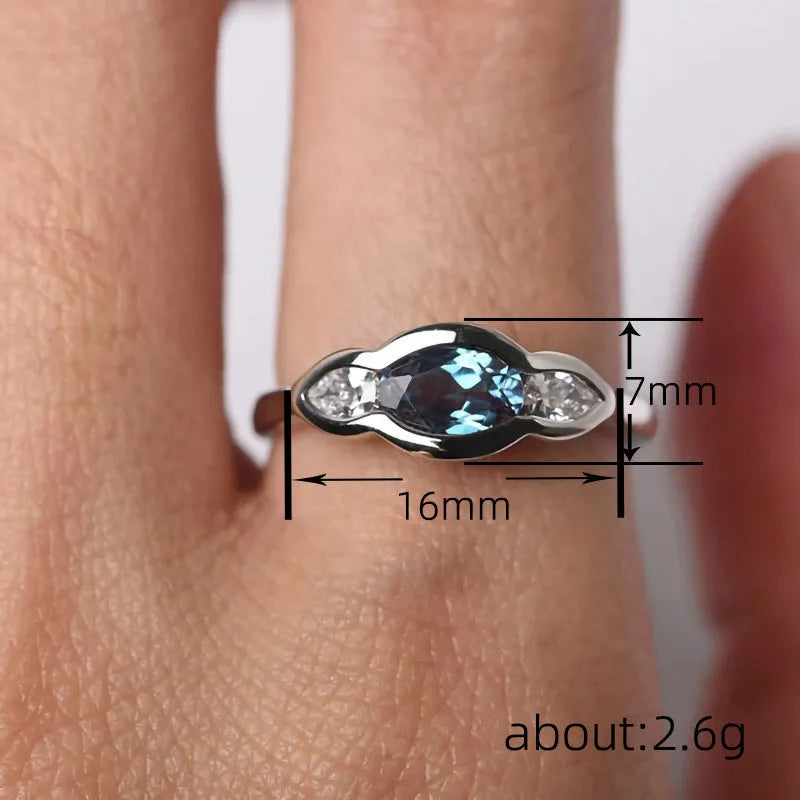 Geometric ellipse copper ring with inlaid zircon stones in white gold finish on a grey background