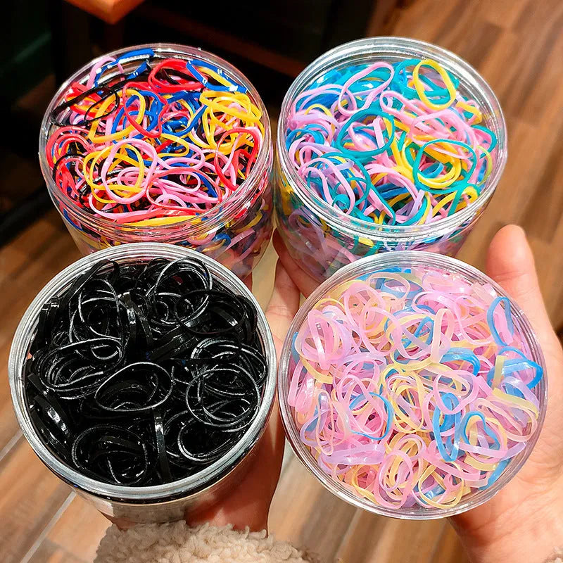 Multi-colour TPU baby hair elastics for toddlers stored in a clear reusable container, showing small and large size options.
