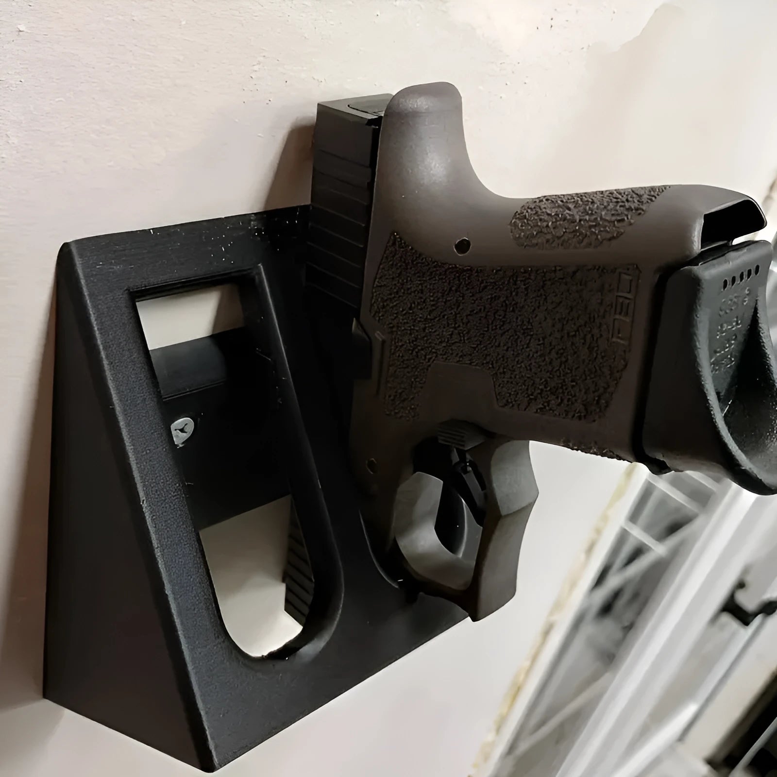 Black plastic pistol display stand for handguns and replicas on a flat surface.