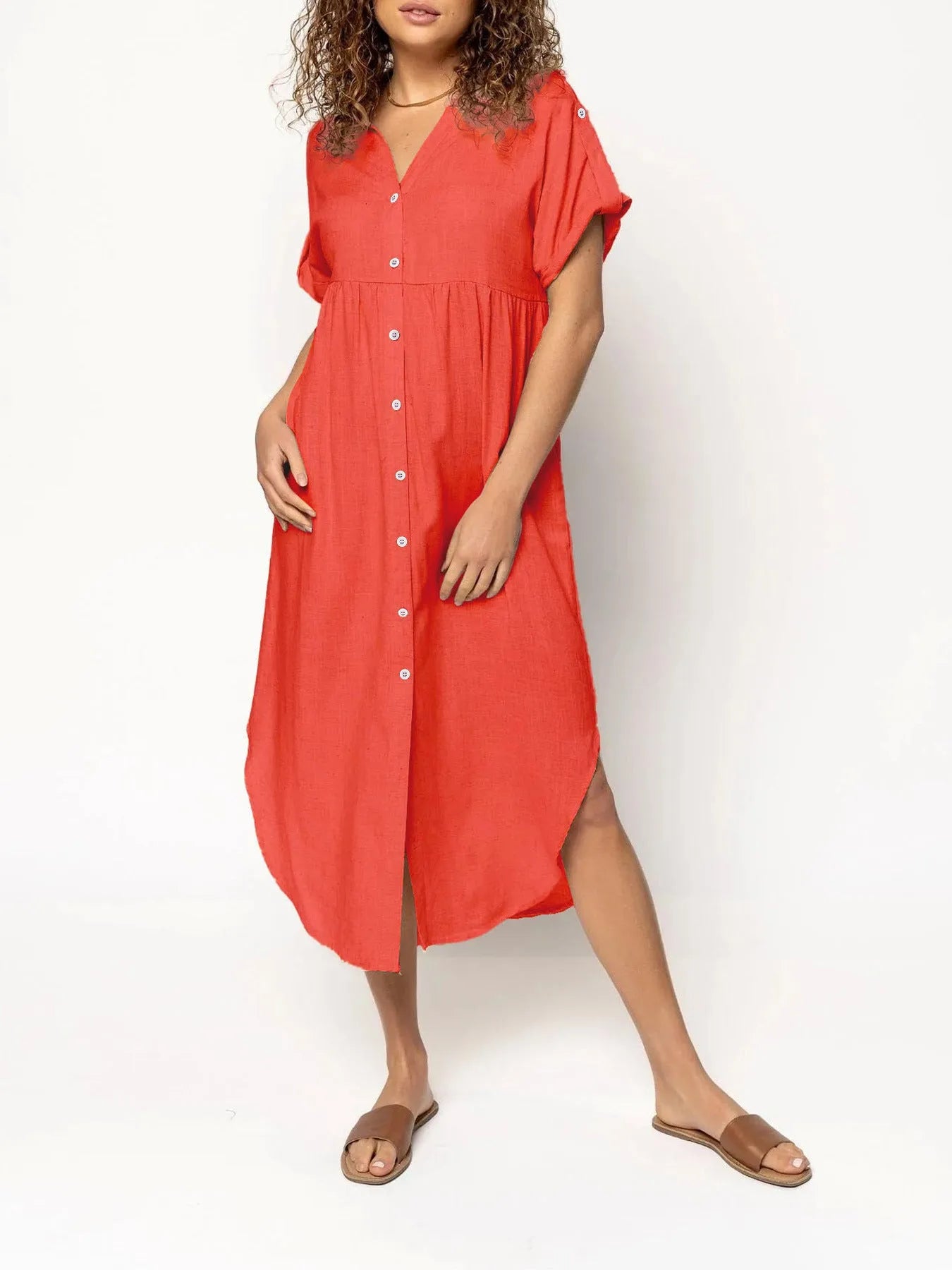 A woman wearing a loose-fitting, mid-length apricot-coloured casual dress with a button-down front.