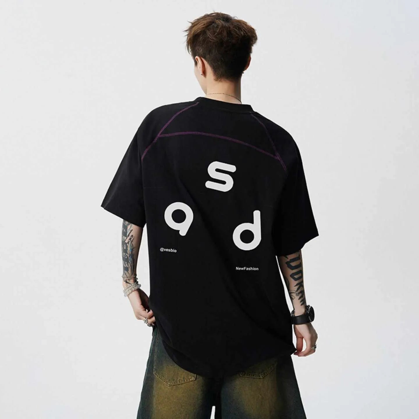 Man wearing a loose fit black cotton t-shirt with a letter print on the chest.