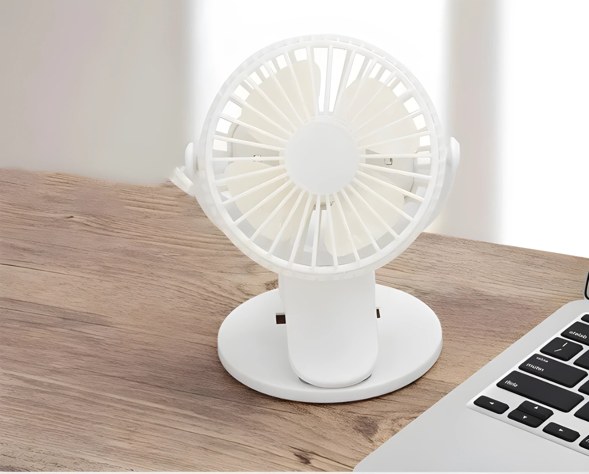 White USB rechargeable mini clip fan with plastic blades attached to a desk edge.