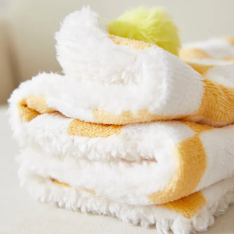 Plush pet blanket with bright plaid pattern and fur ball decorations for cats and dogs