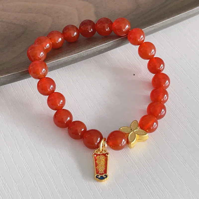 Women's red agate bracelet with manual Chinese dragon and lucky bag designs.