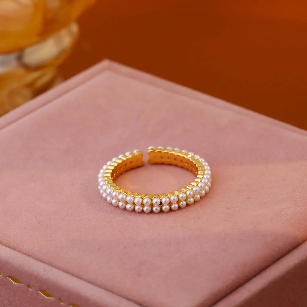 Gold geometric ring with open mouth design and pearl elements on female hand