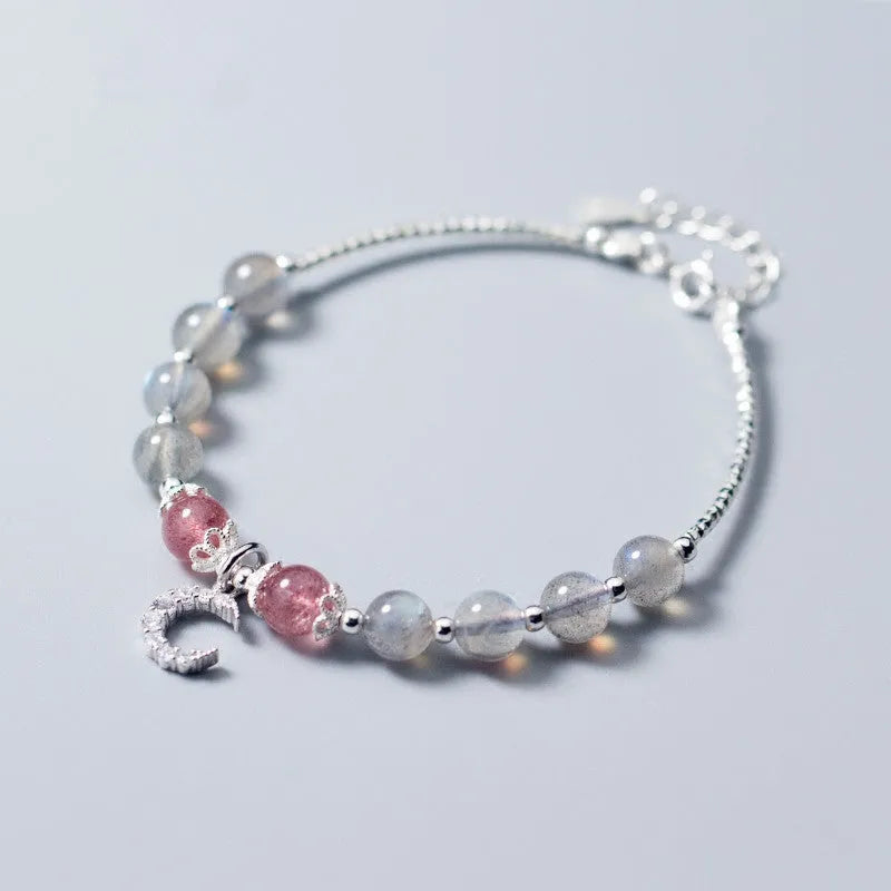 Handmade adjustable moonstone bracelet with silver crescent moon charm and crystal bead on a wrist.