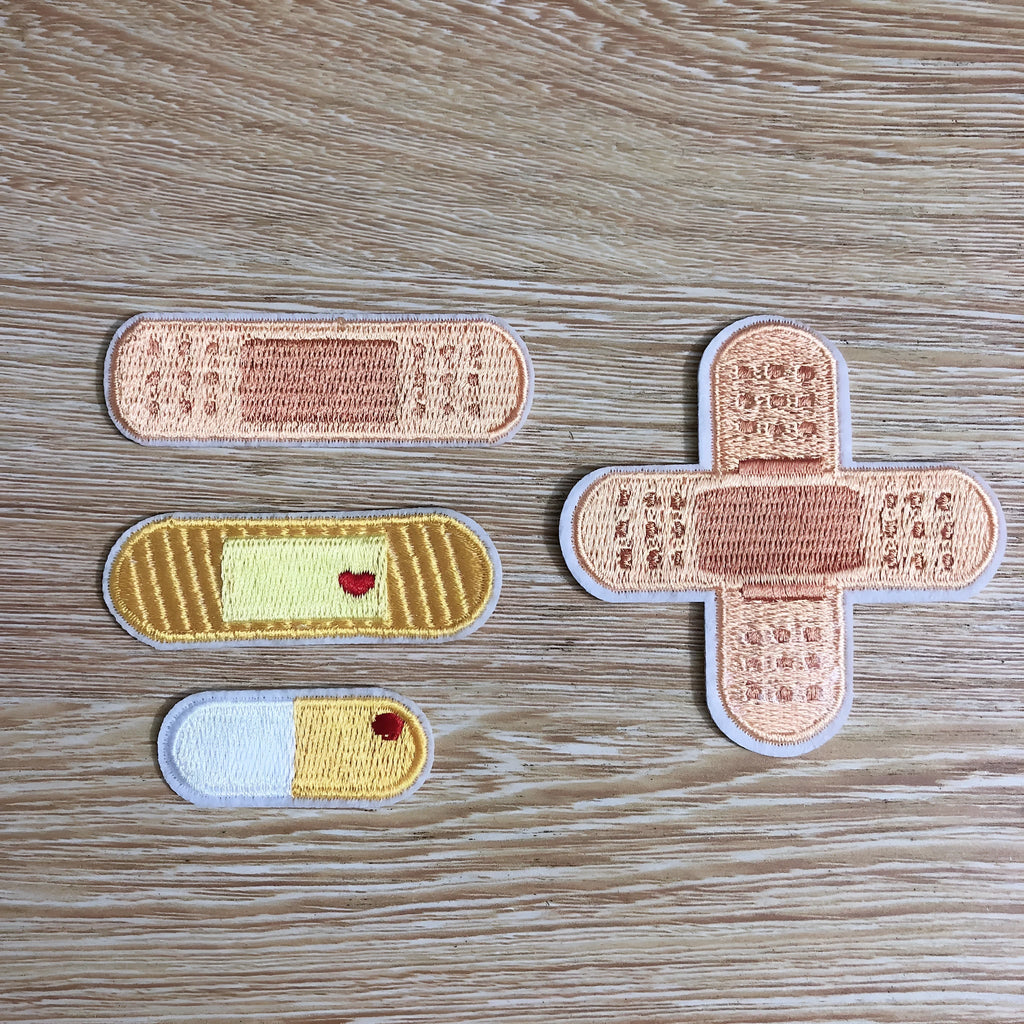 Embroidery detail on iron-on clothing patch with adhesive backing visible