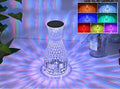 Vase-shaped transparent crystal table lamp with LED colour-changing lights on wooden surface