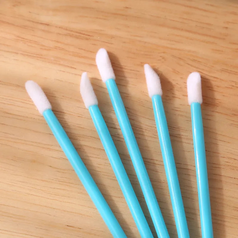 Pack of disposable flocked lip brush applicators with coloured handles on a white surface.