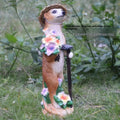 Yellow brown synthetic resin mongoose garden ornament wearing a straw hat and holding a rake or shovel for bonsai decoration