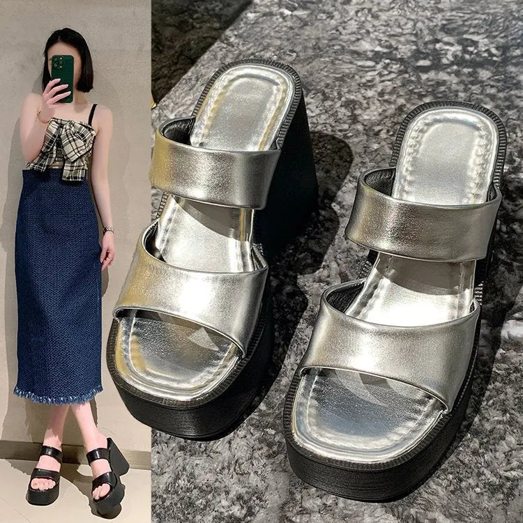 Women's black wedge platform slippers with a square toe on a plain background.