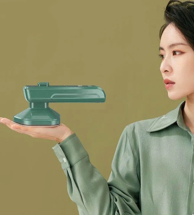 Dark green portable hanging steam iron machine with ceramic panel, shown for scale next to a mobile phone.