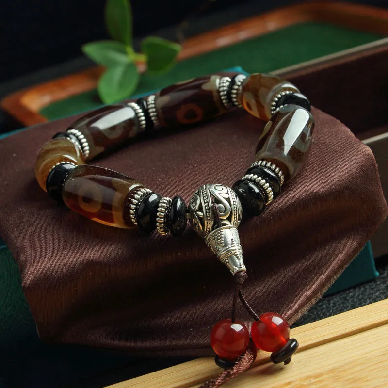 Distressed agate Tibetan bead bracelet with three-eye motifs and polished finish.