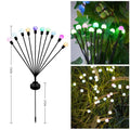 Solar-powered LED ground lamp with multiple heads inserted in garden soil alongside pathway