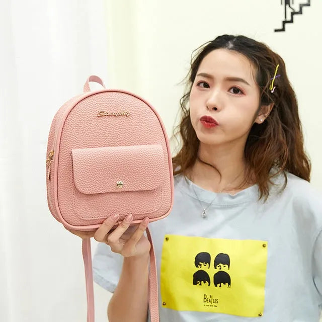 Small black women's PU shoulder backpack worn as backpack, showing zipper closure and compact size