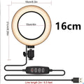 An adjustable live phone stand on a tripod base, extended to show its height range, holding a mobile phone.