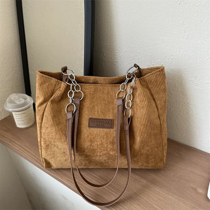 Corduroy one-shoulder tote handbag in a horizontal square shape with a three-dimensional outer pocket.
