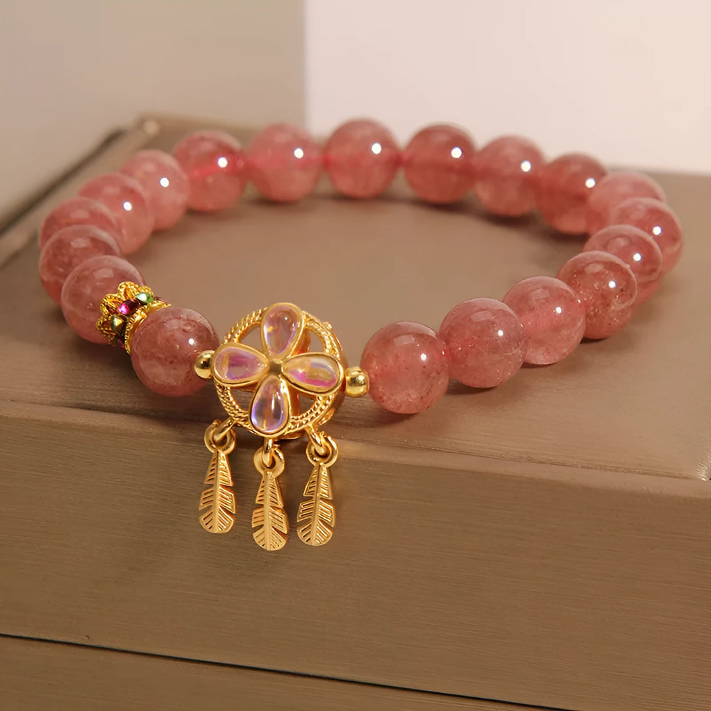 Women's strawberry quartz bracelet with four-leaf dream catcher ball pendant on wrist