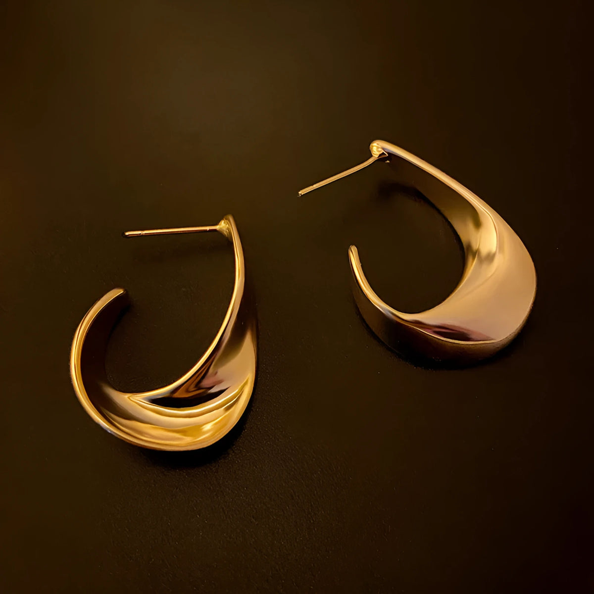 Geometric twisted metal earrings with round elements in gold or silver electroplated finish