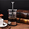 Compact glass stovetop coffee maker with stainless steel components, shown with dimensions 10cm wide and 17cm high.
