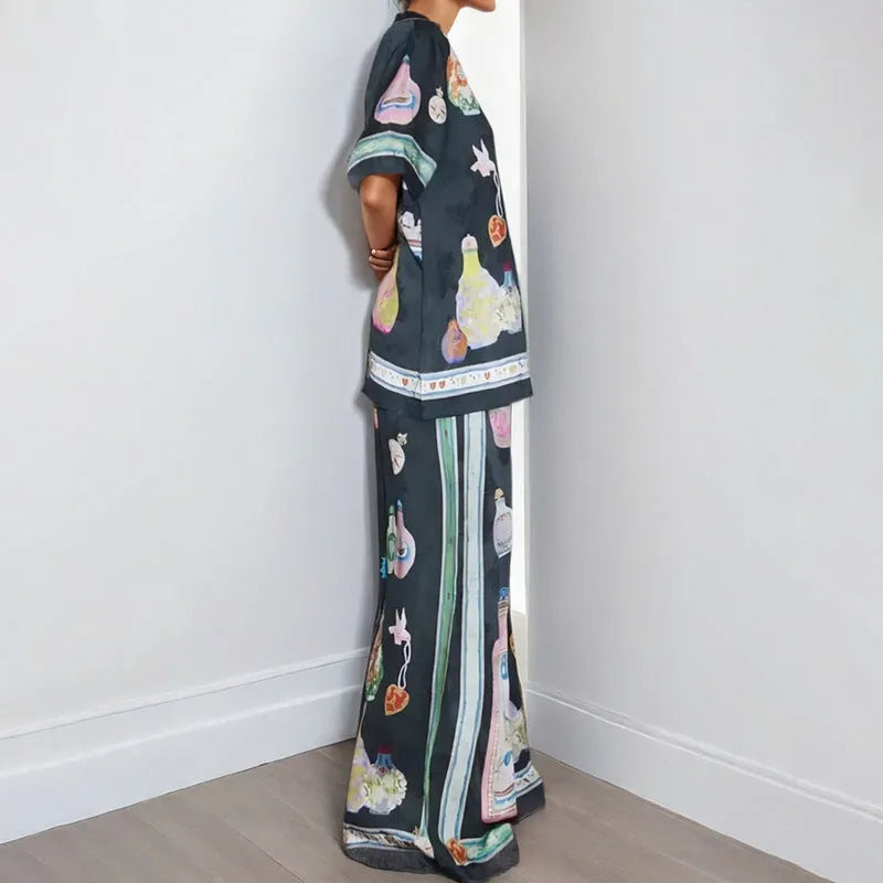 Black women's cardigan and pants set with cartoon animation pattern, shown laid flat.