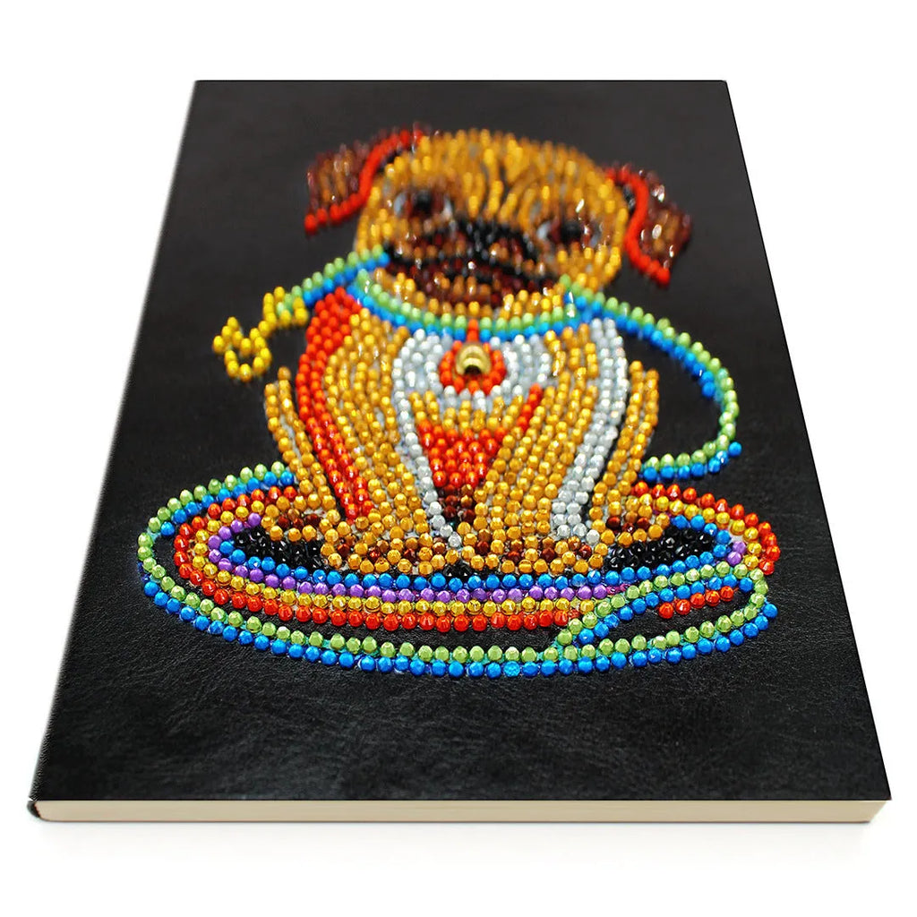 Black hardcover A5 diamond painting notebook with 50 cream pages open on craft table
