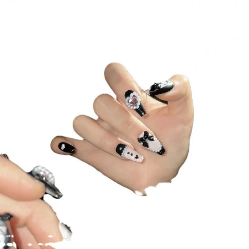Hand-painted black and pink peach heart design on a detachable plastic manicure set with Bow and XINGX patterns.