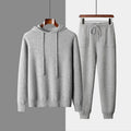 Men's light grey hooded cashmere sweatshirt and matching long pants laid flat as a complete casual winter set.