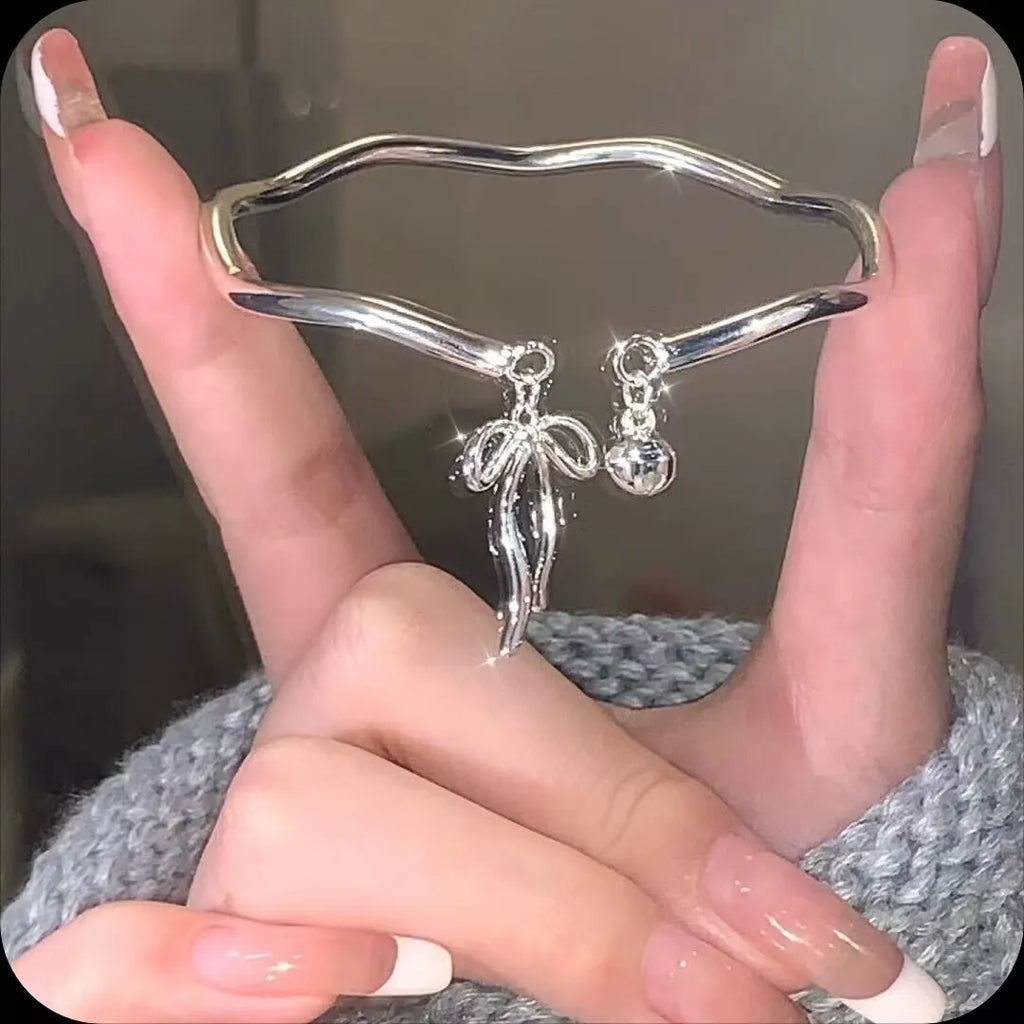 Silver bow adjustable bracelet with bell opening mechanism on wrist