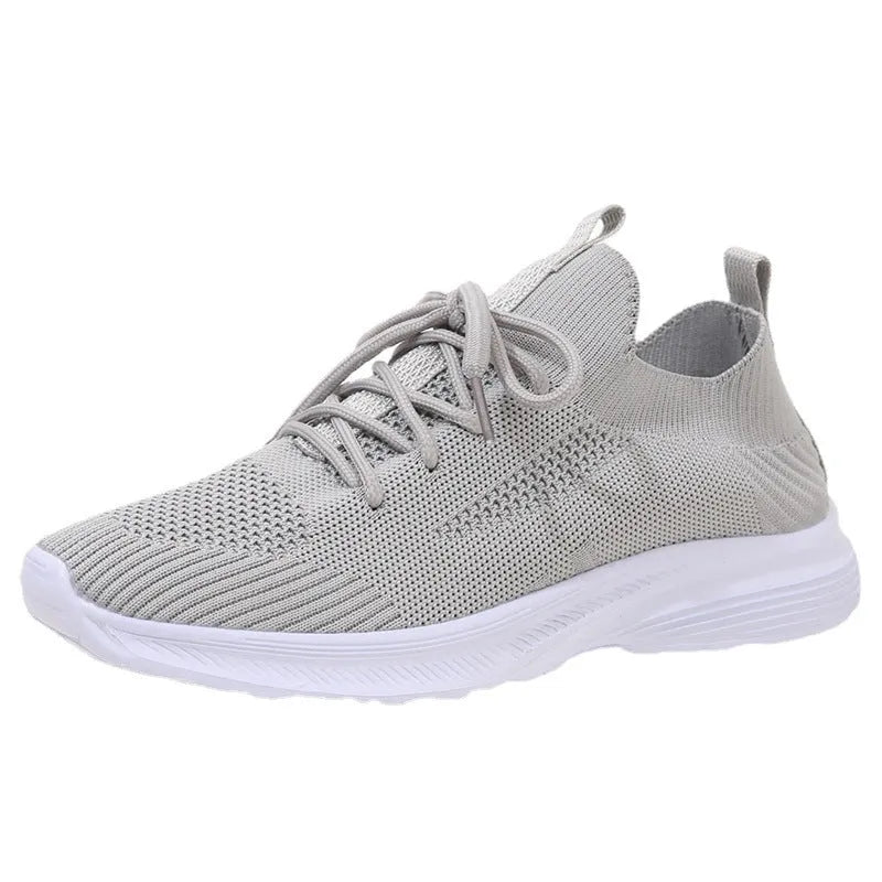 Women's creamy white low-top running shoes with a Flyknit upper and mesh detailing on a flat rubber sole.