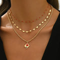 Close-up of a three-layer zinc alloy clavicle chain necklace with geometric shapes and a heart pendant.