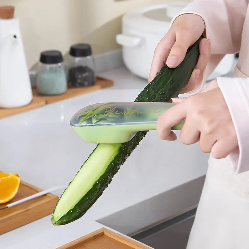 Dark green kitchen peeler with stainless steel blade stored inside its clear plastic storage tube.