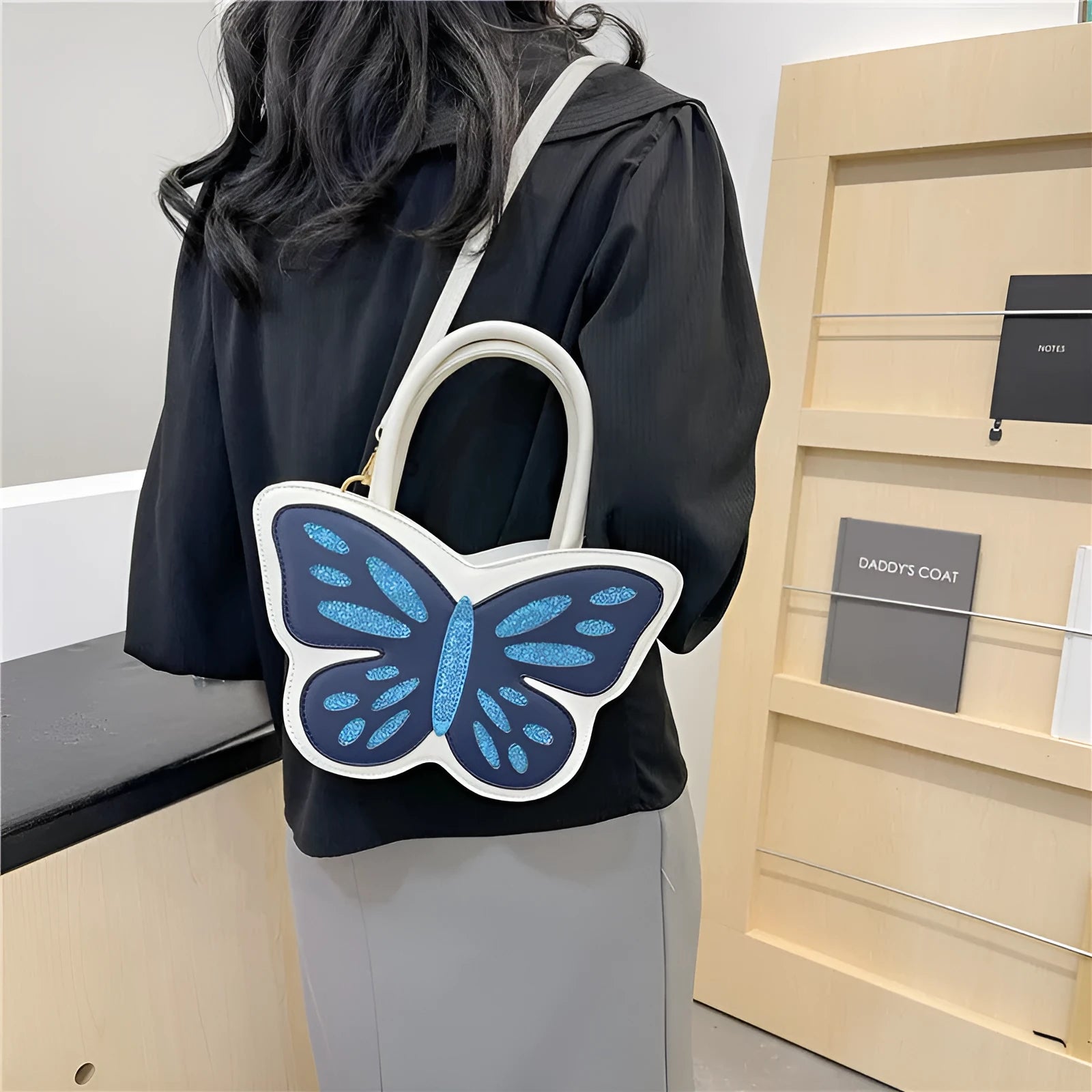 Small square white PU crossbody bag with blue contrast trim on a table.